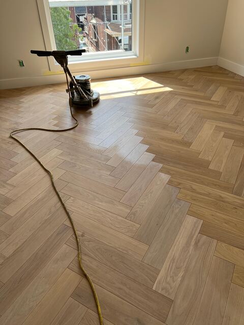 Dust-controlled sanding machine leveling planks on hardwood floor in Washington, DC home